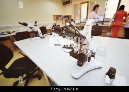 Un infirmier ou scientifique examine les bactéries dans un microscope Banque D'Images