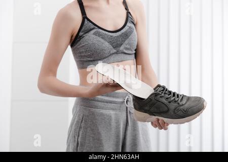 Femme mettant une semelle intérieure orthopédique dans une chaussure à la maison.Sport fille ajustement orthopédique semelle intérieure, gros plan.Bannière de soins des pieds.Correction des pieds plats Banque D'Images