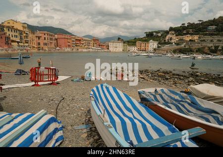 Bateaux sur la plage à rayures bleues sur la baie de Silence, Baia del Silenzio à Sestri Levante, Italie. Destinations de voyage Banque D'Images