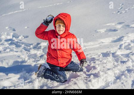 Drôle petit garçon en vêtements d'hiver bleus marche pendant une chute de neige.Activités d'hiver en plein air pour les enfants.Enfant mignon portant un chapeau chaud bas au-dessus de ses yeux Banque D'Images