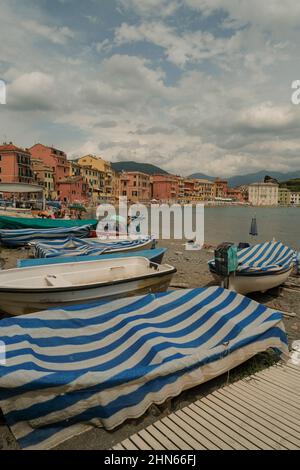 Bateaux garés sur la plage avec une couverture à rayures bleues sur la baie de Silence, Baia del Silenzio à Sestri Levante, Italie. Destinations de voyage Banque D'Images