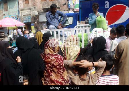 Les gens se sont rassemblés dans une file d'attente pour acheter des sacs de farine sur le prix des subventions d'un magasin de services publics mobiles vendu par le gouvernement de Sindh, comme le prix des articles généraux utilisés quotidiennement ont touché le ciel en raison de la hausse des prix dans le pays, sur une route à Hyderabad le lundi 14 février, 2022. Banque D'Images