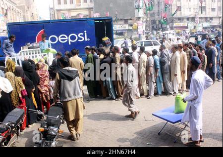 Les gens se sont rassemblés dans une file d'attente pour acheter des sacs de farine sur le prix des subventions d'un magasin de services publics mobiles vendu par le gouvernement de Sindh, comme le prix des articles généraux utilisés quotidiennement ont touché le ciel en raison de la hausse des prix dans le pays, sur une route à Hyderabad le lundi 14 février, 2022. Banque D'Images