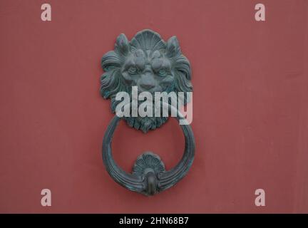 ancienne porte en bois rouge avec une ancienne porte métallique et un knock en forme de lion en gros plan. Design extérieur Banque D'Images