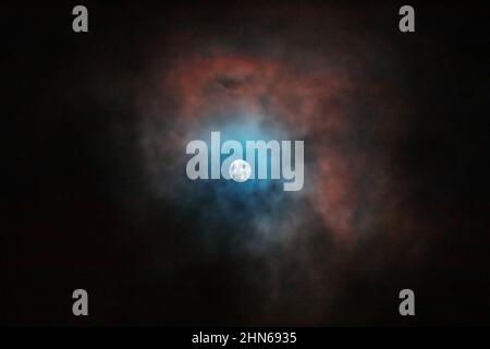 La pleine lune vue à travers des nuages colorés Banque D'Images