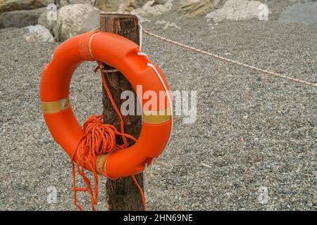 bouée de sauvetage orange en gros plan sur la plage de l'autre côté de la mer, rochers, parasols. sécurité sur la plage Banque D'Images