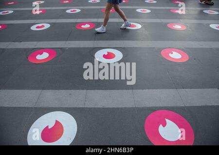 Une femme a vu se promener devant les marqueurs du logo de l'antideroteur social au Temple Trimurti de Bangkok. L'événement « priez et balayez vers la droite » organisé par l'application de rencontres en ligne Tinder, avec des marqueurs de logo social Distancing Tinder sur le terrain de prière, une cabine photo où les gens peuvent prendre des photos de profil pour leurs nouveaux comptes, et des ensembles gratuits, au sanctuaire Trimuriti le jour de la Saint-Valentin à Bangkok, en Thaïlande. Le Trimuriti l'un des dieux hindous est connu pour être le dieu de l'amour. Les gens viennent adorer au sanctuaire de Trimurti avec des offrandes de roses rouges dans l'espoir qu'ils rencontreront leur soulmate. (Photo Banque D'Images
