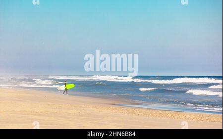 Personne marchant dans l'océan avec un surf Banque D'Images