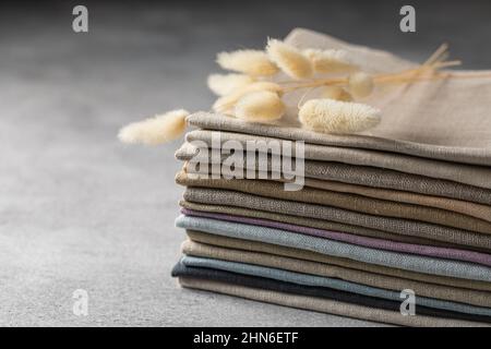 Un tas de quatre tissus en lin naturel aux couleurs ternes et pliés et respectueux de l'environnement sur fond gris Banque D'Images