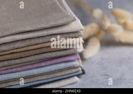 Un tas de quatre tissus en lin naturel aux couleurs ternes et pliés et respectueux de l'environnement sur fond gris Banque D'Images