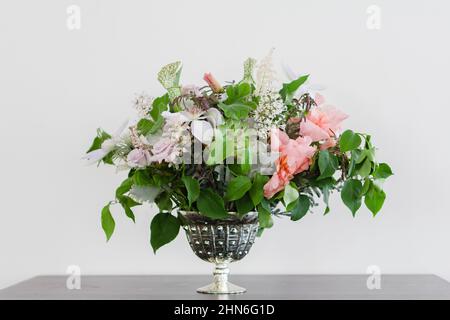 Bouquet de mariée fleuri dans un vase argenté sur une table Banque D'Images