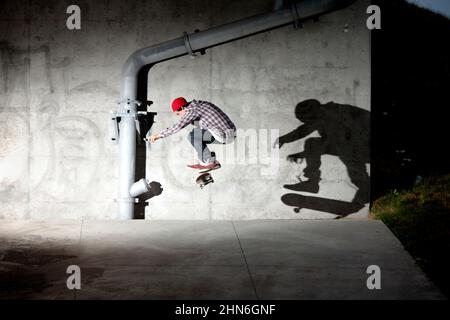 Skateboarder patinant sous le pont de nuit Banque D'Images