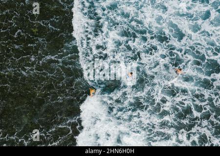 Trois personnes jouant dans les vagues de l'océan à partir d'un drone Banque D'Images