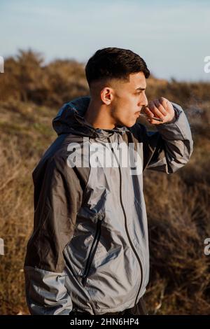 Portrait d'un jeune homme qui fume un joint de marijuana à l'extérieur Banque D'Images