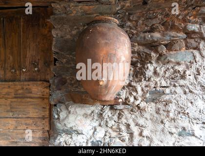 Pot d'argile accroché au mur en pierre à côté d'une porte en bois rustique pour boire du vin Robledillo de Gata Banque D'Images