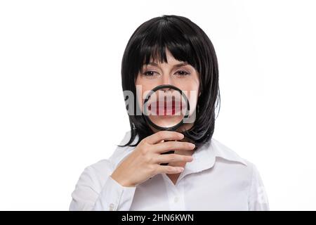 Portrait ironique d'une femme avec loupe devant ses lèvres rouges. Vision ironique et comique de la procédure populaire d'augmentation de lèvre. Banque D'Images