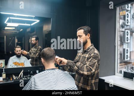 Maître en barbershop fait la coupe de cheveux pour hommes avec la tondeuse cheveux Banque D'Images