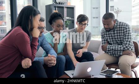 Faire de leurs idées une réalité réussie. 4K séquences vidéo d'un groupe d'hommes d'affaires travaillant sur un ordinateur portable assis sur un canapé dans un bureau. Banque D'Images