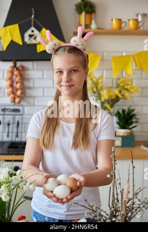 Fille de 12 ans tenant des œufs de Pâques dans la cuisine. Banque D'Images