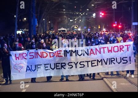 Dresde, Allemagne. 14th févr. 2022. Les participants à une démonstration contre les mesures de Corona marchent le long de l'avenue principale en tenant une bannière indiquant « nous sommes la réponse immunitaire à votre virus système. » Credit: Sebastian Kahnert/dpa-Zentralbild/dpa/Alay Live News Banque D'Images