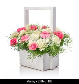 Bouquet de roses roses roses et blanches dans un panier en bois isolé sur fond blanc Banque D'Images