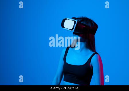 Une femme stupéfait d'avoir une expérience en utilisant des lunettes de réalité virtuelle et en explorant un monde virtuel. Une fille passe son temps en métaverse tout en se traînant Banque D'Images