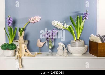 Jacinthe blanche dans un grand bol en porcelaine, figurines de lièvres et un oiseau, sont sur la cheminée contre le mur bleu foncé. Mise en page. Concept de ressort Banque D'Images