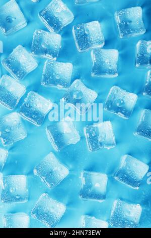 Beaucoup de glaçons glacés et rafraîchissants avec des gouttes sur fond bleu. Boissons rafraîchissantes par temps chaud Banque D'Images