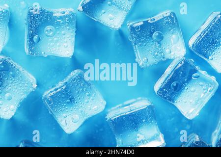 Beaucoup de glaçons glacés et rafraîchissants avec des gouttes sur fond bleu. Boissons rafraîchissantes par temps chaud Banque D'Images