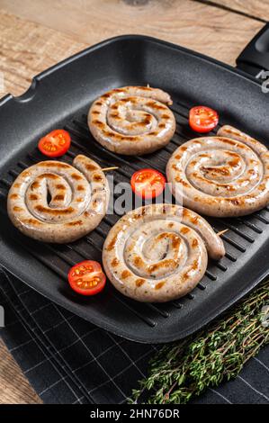 Frits sur une poêle à frire saucisses à viande en spirale avec épices. Arrière-plan en bois. Vue de dessus Banque D'Images