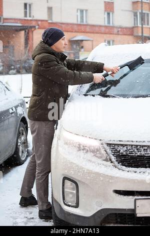 Le conducteur retire la neige de l'avant de son véhicule utilitaire sport enneigé, balayant la glace du pare-brise Banque D'Images