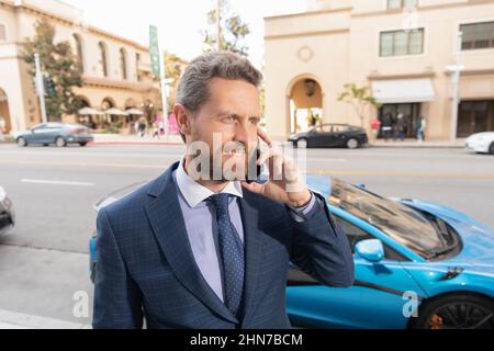 loueuse de voiture heureuse parlant au téléphone à l'extérieur Banque D'Images