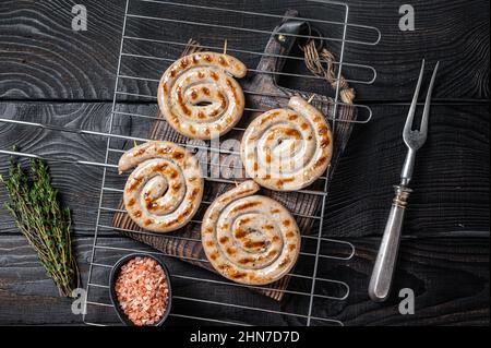 Barbecue de saucisses de viande de porc en spirale grillées sur un grill. Arrière-plan noir. Vue de dessus Banque D'Images