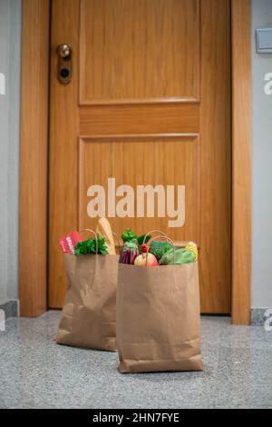 Des sacs de shopping de nourriture sont à la porte de la maison ou de l'appartement.Livraison de légumes et de fruits pendant la quarantaine et l'auto-isolement. Banque D'Images