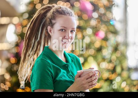 Jeune femme joyeuse avec une tasse de thé à l'intérieur. Banque D'Images