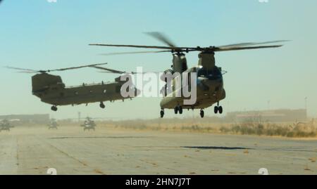 Avec les hélicoptères UH-60 Blackhawk à proximité, deux hélicoptères CH-47 Chinook, affectés au bataillon de soutien général de l'aviation 2-501st, commencent à s'envoiser au-dessus d'une piste d'atterrissage alors qu'ils commencent leur mission de s'emparer d'un terrain d'aviation à fort Bliss Biggs Field, le 22 février 2022. 2-501st a été responsable du remplissage de 120 personnes au sol dans un champ d'aviation comme moyen d'agresser et de s'emparer de l'emplacement. (É.-U. Photo de l'armée par le Sgt. David Cordova, 24th Theatre public Affairs support Element) Banque D'Images