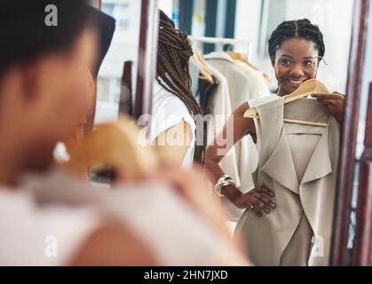 C'est juste la mise à jour de ma garde-robe. Coupe courte d'une femme dans un magasin tenant un vêtement devant elle dans le miroir. Banque D'Images