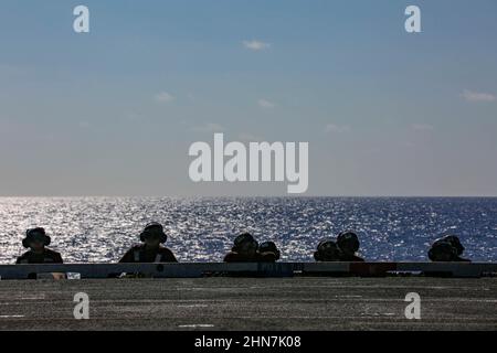 MER DES PHILIPPINES (fév 13, 2022) des marins de la Marine américaine avec le porte-avions de la classe Nimitz USS Abraham Lincoln (CVN 72) observent les opérations de vol sur le pont de vol à l'appui de l'exercice Jungle Warfare 22 (JWX 22) à travers Okinawa, au Japon, le 13 février 2022. JWX 22 est un exercice de formation sur le terrain à grande échelle axé sur l'exploitation des capacités intégrées des partenaires conjoints et alliés pour renforcer la sensibilisation, les manœuvres et les incendies de tous les domaines dans un environnement maritime distribué. (É.-U. Photo de la marine par la spécialiste en communication de masse apprenti Julia Brockman) Banque D'Images