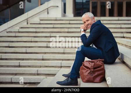 L'air frais empêche mes idées de devenir obsolètes. Portrait d'un homme d'affaires confiant assis sur les escaliers à l'extérieur de son immeuble de bureaux. Banque D'Images