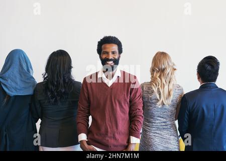 Ne tournez jamais le dos à l'occasion. Portrait d'un jeune homme d'affaires gai debout dans la ligne en attendant une entrevue et le reste de la Banque D'Images