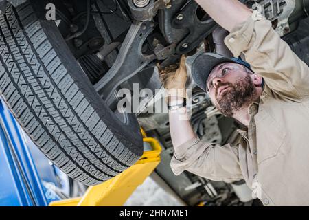 Résolution de problèmes de suspension de véhicule moderne par le mécanicien de voiture caucasien professionnel dans son 30s. Emploi dans l'industrie automobile. Banque D'Images