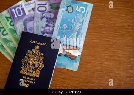 Vue du passeport canadien avec de l'argent canadien sur fond marron. Banque D'Images