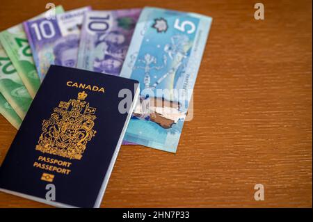 Vue du passeport canadien avec de l'argent canadien sur fond marron. Banque D'Images