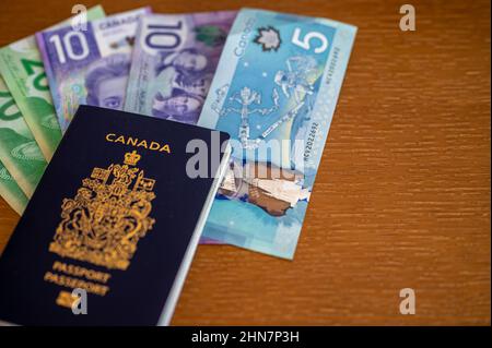 Vue du passeport canadien avec de l'argent canadien sur fond marron. Banque D'Images