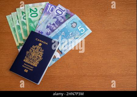 Vue du passeport canadien avec de l'argent canadien sur fond marron. Banque D'Images