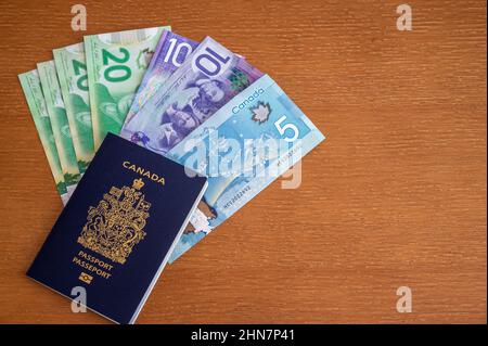 Vue du passeport canadien avec de l'argent canadien sur fond marron. Banque D'Images