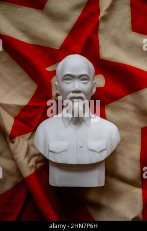 Buste de Ho Chi Minh devant un drapeau communiste. Banque D'Images