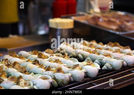 Des escargots d'escargot grillés sont servis comme encas dans le magasin extérieur du marché de JIU Fen à Taïwan. Ils sont servis avec du sel, du poivre noir et de la sauce chaude. Banque D'Images