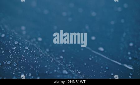 Gros plan de gouttes d'eau de pluie sur la tente. La rosée tombe sur la texture du tissu de tente touristique dans les rayons du soleil levant ou fixant. Camp, tourisme de randonnée. La pluie pleut sur la tente. Banque D'Images