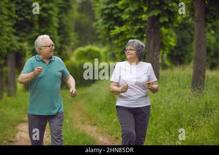 Couple senior heureux de faire du jogging tout en profitant d'une séance d'entraînement physique active dans le parc ensemble Banque D'Images